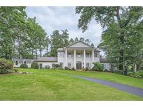 Stately white brick home with mature trees, a manicured lawn, and a circular driveway exudes classic elegance at 111 Cherry Hill Dr, Marietta, GA 30067