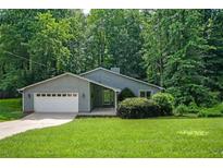 Charming single-story home with a well-manicured lawn and an attached garage, nestled amongst mature trees at 4766 Jamerson Forest Cir, Marietta, GA 30066