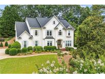 Stunning two-story white home with lush landscaping, offering timeless elegance and curb appeal at 505 Woodmoore Ct, Sandy Springs, GA 30342