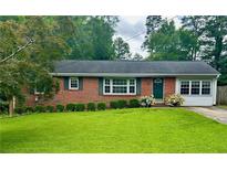 Charming brick home with a well-manicured lawn and lush greenery at 1468 Spruce Se Dr, Smyrna, GA 30080