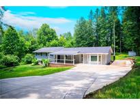 Charming single-story home with a long driveway and well-manicured lawn surrounded by lush trees at 241 Sarann Nw Ct, Lilburn, GA 30047