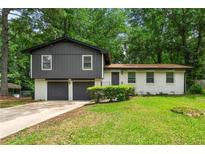 Charming split-level home featuring a two-car garage, neutral paint scheme, and a spacious front yard at 586 Chris Cir, Lawrenceville, GA 30044