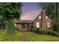 Charming brick home featuring a chimney and covered front porch, nestled in a lush, green landscape at 6230 S Summers S Cir, Douglasville, GA 30135