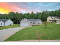 Charming, single-story home with gray siding, green lawn and beautiful sunset background at 275 Green Commons Dr, Covington, GA 30016