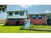 Two-story home with red brick facade, carport, white trim, and blue shutters at 472 Opel St, Riverdale, GA 30274