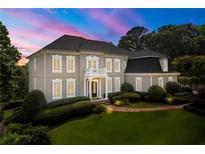 Stately home featuring manicured landscaping, a covered entrance, and beautiful architectural details against a colorful twilight sky at 4720 Cliffside Ct, Marietta, GA 30067