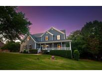 Charming two-story home with a well-manicured front yard and inviting covered porch at 1851 Harvest Way, Loganville, GA 30052