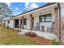 Inviting front porch with rocking chairs and wooden columns, perfect for relaxing and enjoying the outdoors at 4739 Lower Jersey Rd, Oxford, GA 30054
