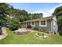 A single-story home with a landscaped front yard featuring a stone fire pit and lush greenery at 1550 Bells Ferry Rd, Marietta, GA 30066