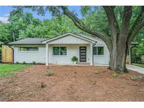 Charming single-story home with painted brick, mature trees, and minimalist landscaping at 3052 Brook Dr, Decatur, GA 30033