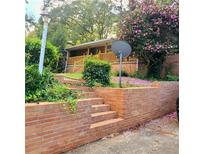 Charming front yard with a brick retaining wall, steps and mature landscaping including blooming flowering tree at 1723 Fort Valley Sw Dr, Atlanta, GA 30311
