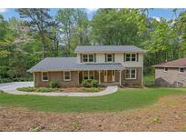 Charming two-story home featuring a brick facade, complemented by a beautifully landscaped front yard with mature trees at 3512 Hidden Acres Dr, Atlanta, GA 30340