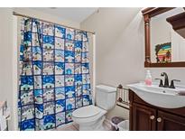 Cozy bathroom featuring a quirky shower curtain, single sink vanity and an updated toilet at 561 Holland Rd, Dallas, GA 30157