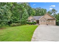 Charming home featuring stone accents, a well-manicured lawn, and an attached two-car garage at 561 Holland Rd, Dallas, GA 30157