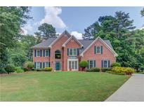 Charming two-story brick home featuring a manicured lawn and mature trees on a beautiful lot at 1721 Crowes Lake Ct, Lawrenceville, GA 30043