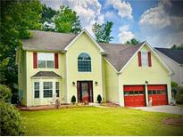 Charming two-story home with yellow siding, red shutters and garage doors, and a well-manicured lawn at 475 Cascade Rise, South Fulton, GA 30331