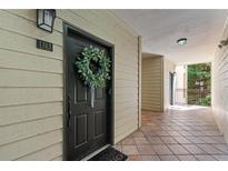 Inviting front door with wreath and sidelight on a covered porch with tiled floor and cream-colored siding at 3777 Peachtree Ne Rd # 1313, Brookhaven, GA 30319