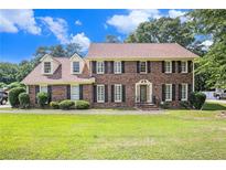 Charming two-story brick home with manicured lawn, dormer windows, and classic black shutters at 4837 Mystere Sw Cir, Lilburn, GA 30047