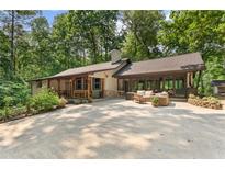 Charming single-story home featuring a large drive and outdoor seating area surrounded by lush greenery at 4025 Demooney Rd, Atlanta, GA 30349