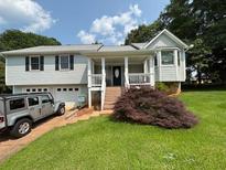 Charming home with light blue siding, a well-manicured lawn, and a mature shrub in the front yard at 403 Hickory Walk, Woodstock, GA 30188