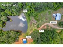 Expansive Palmetto, GA property featuring a home, pond, RV shed, and shed, all surrounded by lush greenery at 6160 Campbellton Redwine Rd, Chattahoochee Hills, GA 30268