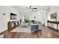 Bright living room with hardwood floors, neutral tones, and modern furnishings, with a large sectional sofa at 833 Society Ct, Woodstock, GA 30188