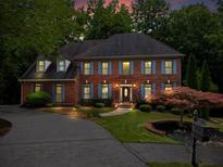 Charming two-story brick home with manicured lawn, blue shutters and a welcoming front entrance at 2910 Leeds Garden Ln, Alpharetta, GA 30022