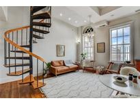 Bright living room featuring a spiral staircase, hardwood floors, and large windows with city views at 30 5Th Ne St # 1006, Atlanta, GA 30308