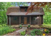 Charming log cabin with a covered porch, stone walkway, and well-manicured landscaping at 15 Bailey St, Whitesburg, GA 30185