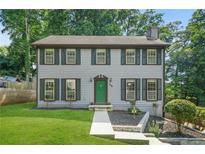 Charming two-story home with a well-manicured front yard, gray siding and dark shutters and a bright green door at 998 Pointer Rdg, Tucker, GA 30084
