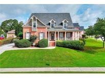 Charming brick home with manicured lawn, lush landscaping, and a welcoming front porch perfect for relaxing outdoors at 3145 Sweet Basil Ln, Loganville, GA 30052