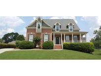 Charming brick two-story home with a welcoming front porch and well-manicured landscaping at 3145 Sweet Basil Ln, Loganville, GA 30052
