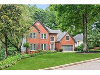 Charming two-story brick home featuring a manicured lawn and attached two-car garage at 2220 Cape Courage Way, Suwanee, GA 30024