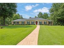 Charming ranch-style home featuring a manicured lawn, stone walkway, and a classic red front door at 3244 Beechwood Se Dr, Marietta, GA 30067