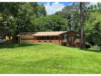 Charming brick ranch home with a well-manicured lawn and attached garage on a beautiful sunny day at 5607 Mountainbrooke Ct, Stone Mountain, GA 30087