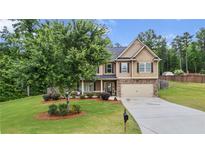 Charming two-story home featuring a manicured lawn, mature tree, and inviting front porch at 572 Boulder View Pkwy, Dallas, GA 30157
