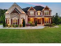 Charming stone home featuring an expansive lawn, manicured landscaping, and a welcoming front entrance at 1835 Henley Way, Alpharetta, GA 30009