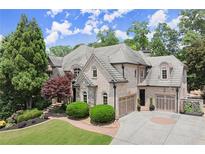 A charming brick home with manicured landscaping, a circular driveway, and a three-car garage under a blue sky at 4105 Cougar Ne Pt, Marietta, GA 30066