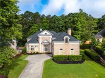 Elegant brick home featuring a circular driveway, lush landscaping, and a classic architectural design at 8370 Royal Melbourne Way, Duluth, GA 30097