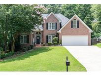 Beautiful brick home featuring a manicured lawn, mature trees and an attached two car garage at 1418 Winborn Nw Cir, Kennesaw, GA 30152