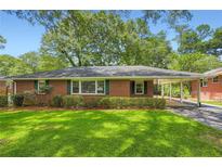 Charming brick home featuring a well-manicured lawn, a covered carport, and lush landscaping creating welcoming curb appeal at 739 Pinehill Se Dr, Smyrna, GA 30080