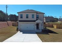 Charming two-story home with a well-maintained lawn, long driveway, and attached two-car garage at 301 Amsterdam Way, Hampton, GA 30228