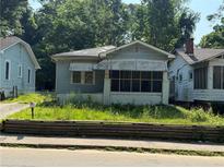 Charming, light blue one-story home featuring a screened-in porch and a small, overgrown front yard at 501 Holly Nw St, Atlanta, GA 30318