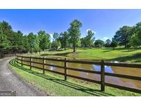 Scenic pond with wooden fence and green surroundings adding natural charm to the property at 228 Indian Creek Rd, Locust Grove, GA 30248