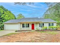 Charming single-story home with a vibrant red front door and a well-maintained front yard and attached garage at 4547 Atha Cir, Loganville, GA 30052