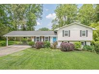 Charming split-level home featuring a manicured lawn, bright blue door, and covered carport, inviting you to call it home at 205 Plantation Sw Rd, Smyrna, GA 30082