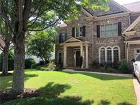 Beautiful brick two-story home featuring a well-manicured front yard with lush green grass and mature shade trees at 1450 Liberty Ln, Cumming, GA 30040