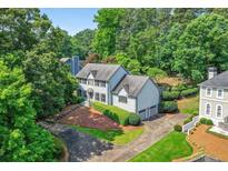 Stately two-story home with a manicured lawn, mature trees, and a circular driveway, offering curb appeal at 3185 Country Club Nw Ct, Kennesaw, GA 30144