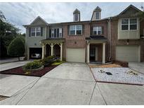 Charming townhome featuring brick facade, attached garage, and beautifully landscaped front yard at 1649 Southgate Mill Nw Dr, Duluth, GA 30096