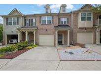Three-story townhome with brick facade, attached garage, and well-maintained landscaping at 1649 Southgate Mill Nw Dr, Duluth, GA 30096